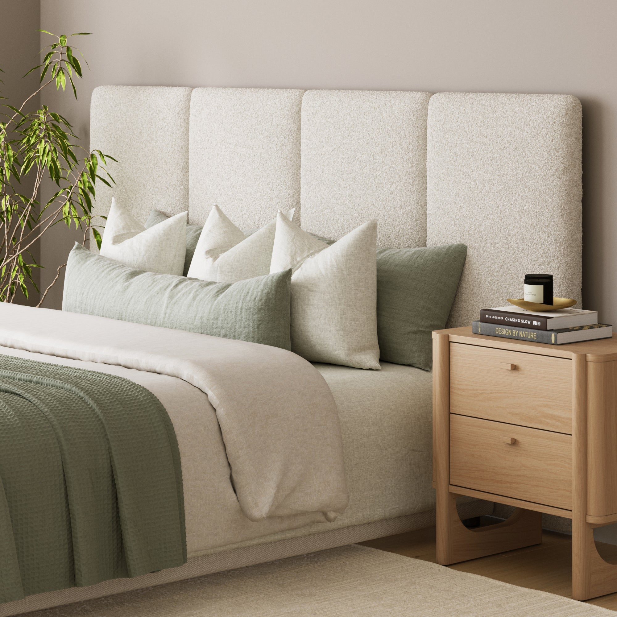 A modern bedroom featuring the Nathan James Wall Mounted 4 Panel Boucle Headboard for King Bed, green and beige pillows, a matching green blanket, a light wood nightstand with books and candle, and a leafy plant for mid-century modern style.