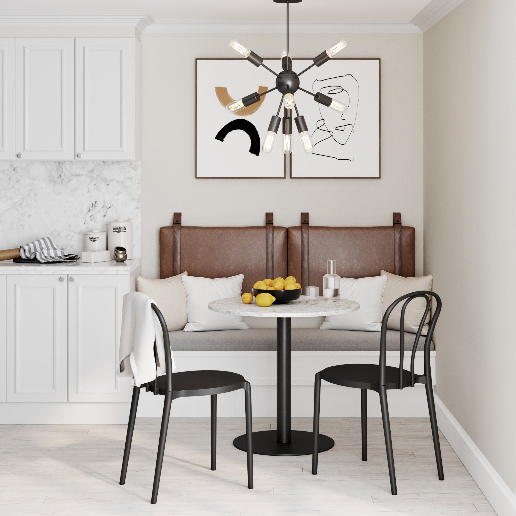 A modern dining nook with a round marble table, two black chairs, a cushioned bench with brown leather backrests, a bowl of fruit, abstract wall art, and a contemporary chandelier in a bright kitchen.