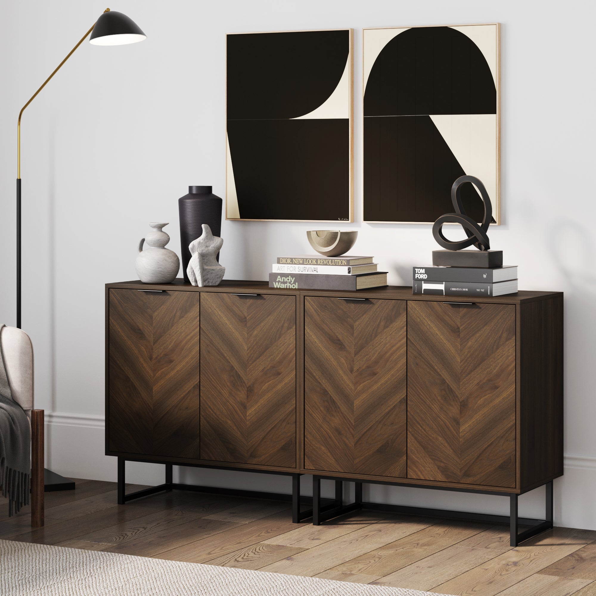 The Nathan James Wood Herringbone TV Console Credenza Walnut (Set of 2) stands against a white wall, topped with abstract black-and-white art, decorative sculptures, stacked books, and paired with a tall black floor lamp.