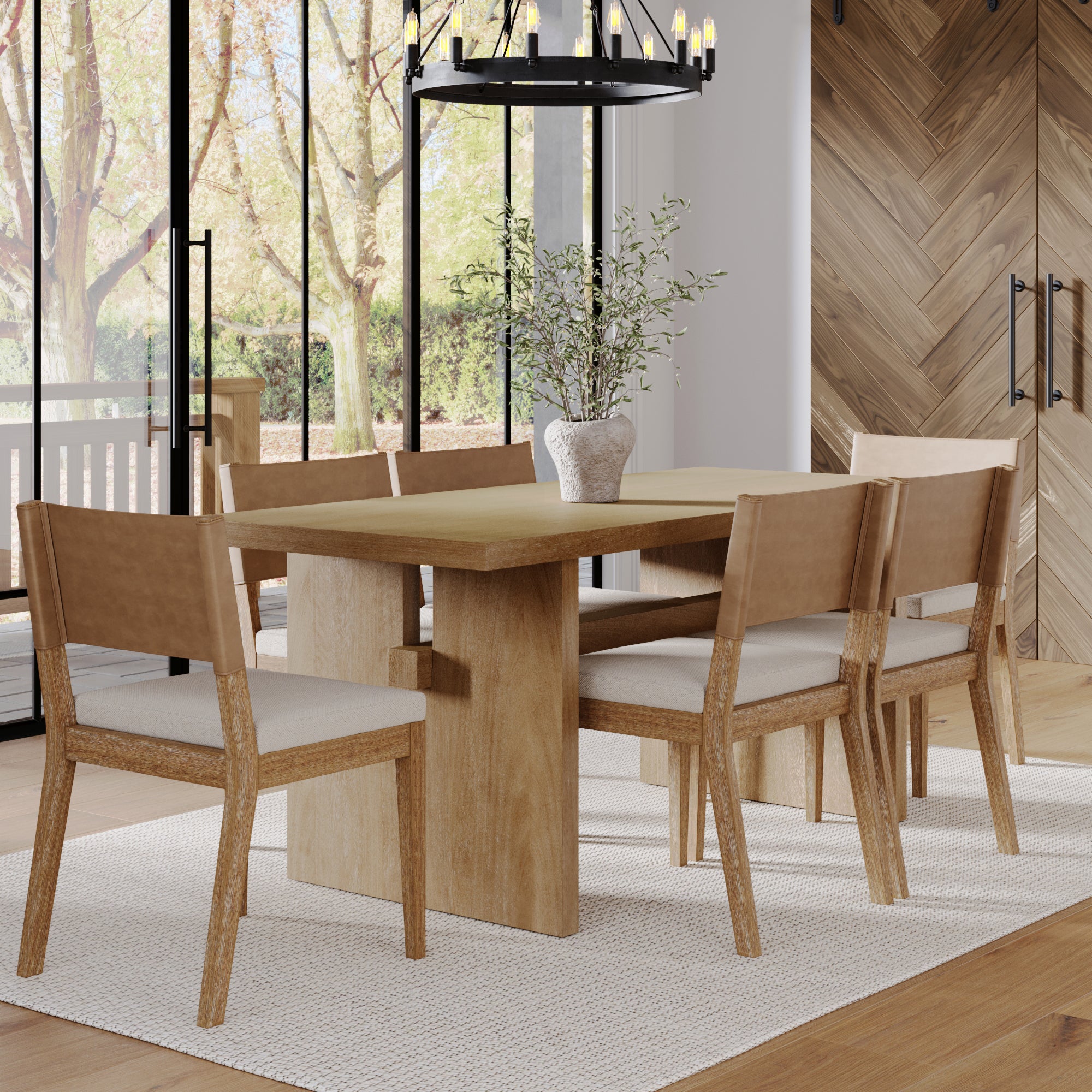 A modern dining room features the Nathan James Farmhouse Dining Set with a solid wood table and six matching chairs with beige cushions, a potted plant centerpiece, white rug, large windows, wood-paneled walls, and abundant natural light.