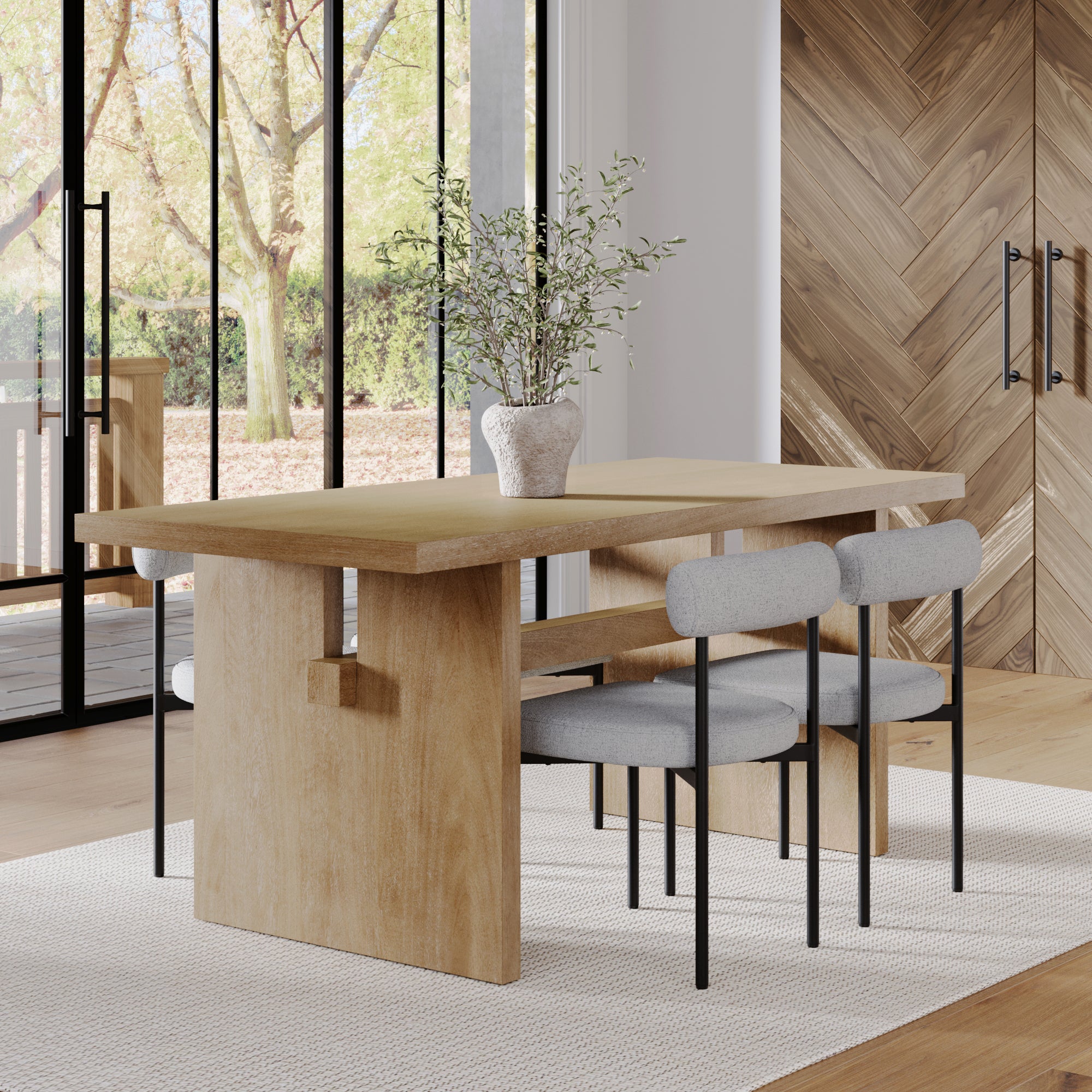 A modern dining room showcases the Nathan James Mid-Century Dining Set Feather Gray (4 Chairs), a sleek table, and four cushioned gray chairs—complemented by a white vase with greenery, treetop views through large windows, and wood accents.