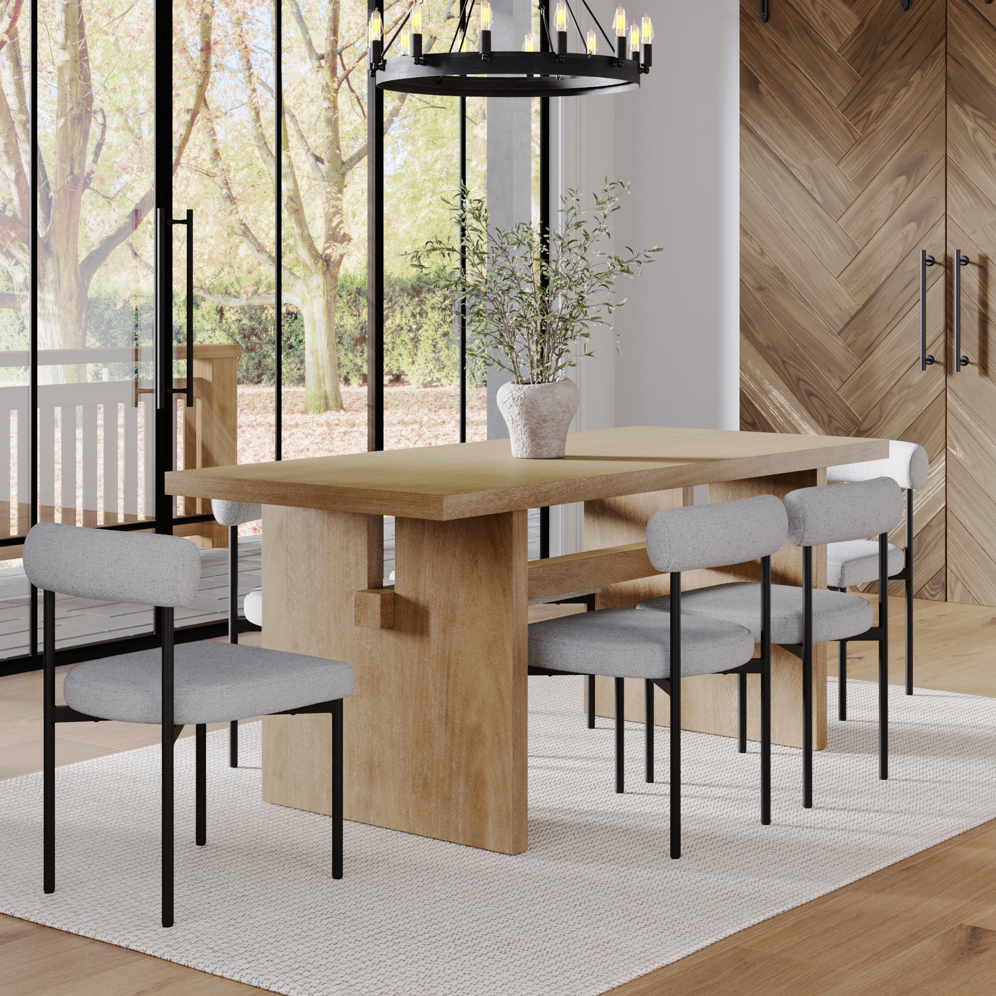 A modern dining room showcases the Nathan James Mid-Century Dining Set Feather Gray (6 Chairs), paired with a potted plant centerpiece, chandelier, herringbone wood walls, and large windows overlooking trees and a porch.