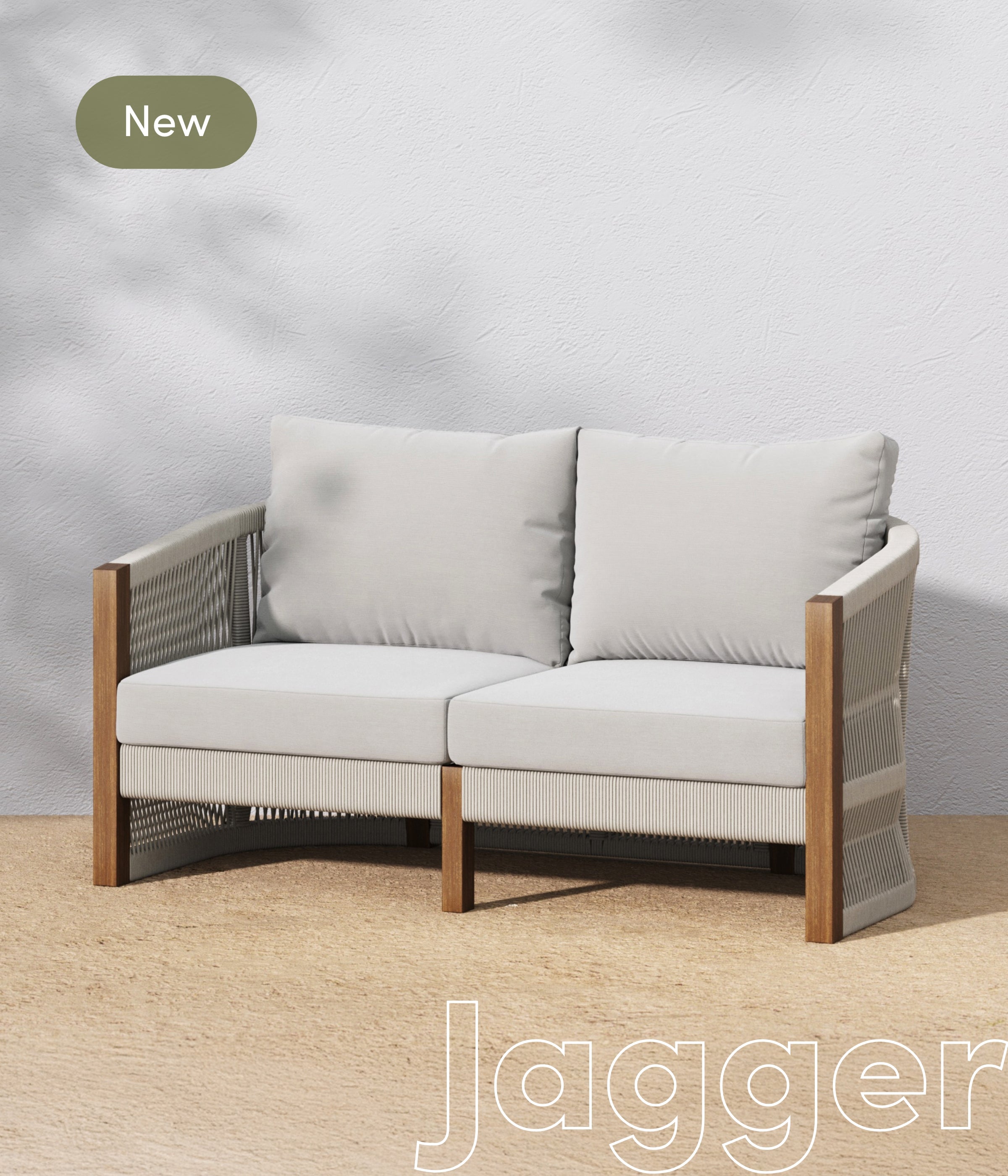 A modern, light gray two-seater sofa with wooden armrests and woven side panels sits on a beige floor against a white wall. A green label in the top left corner reads New, and Jagger is written in large text at the bottom.