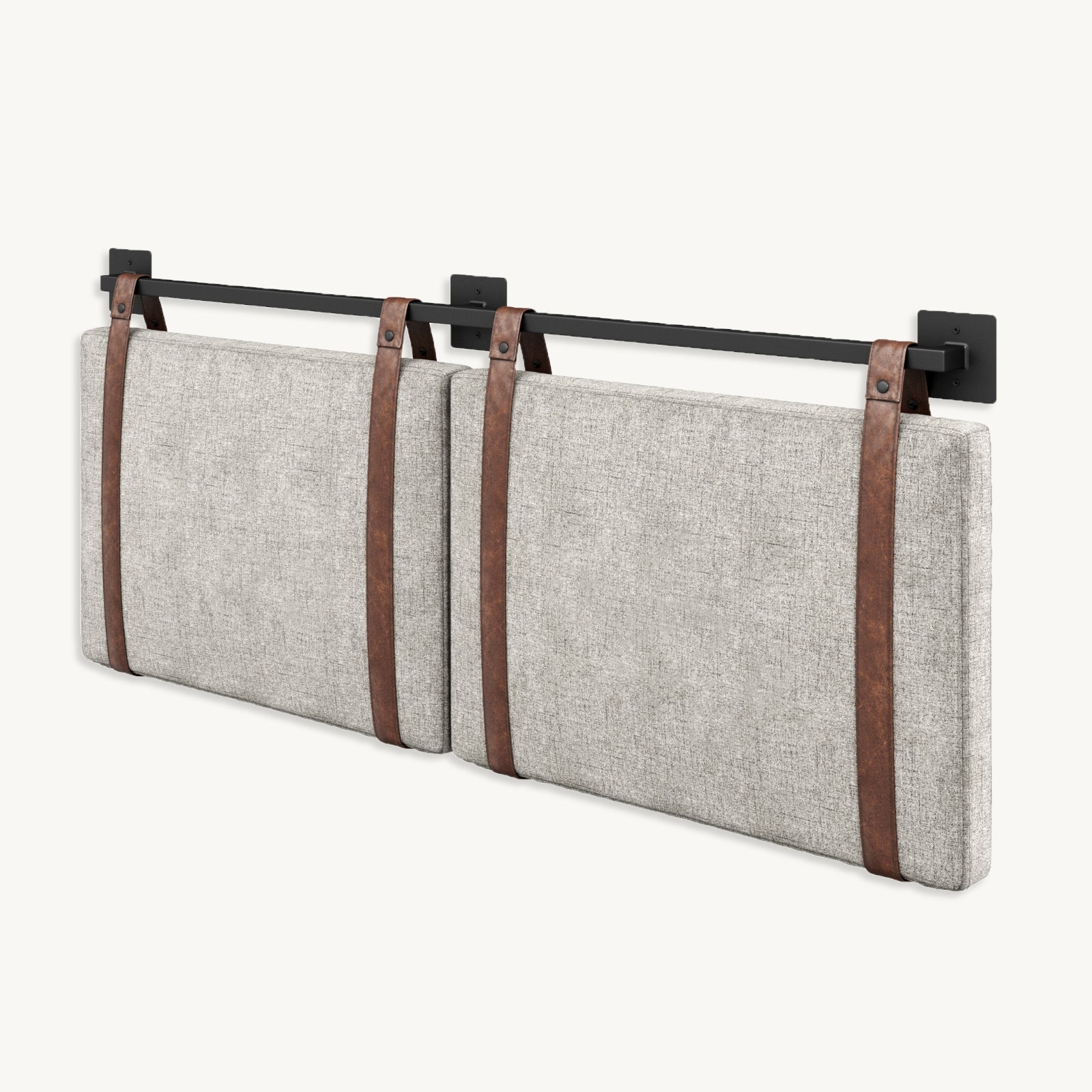 Two rectangular light gray upholstered cushions are mounted horizontally on a wall using brown leather straps that hang from a black metal rail with brackets.