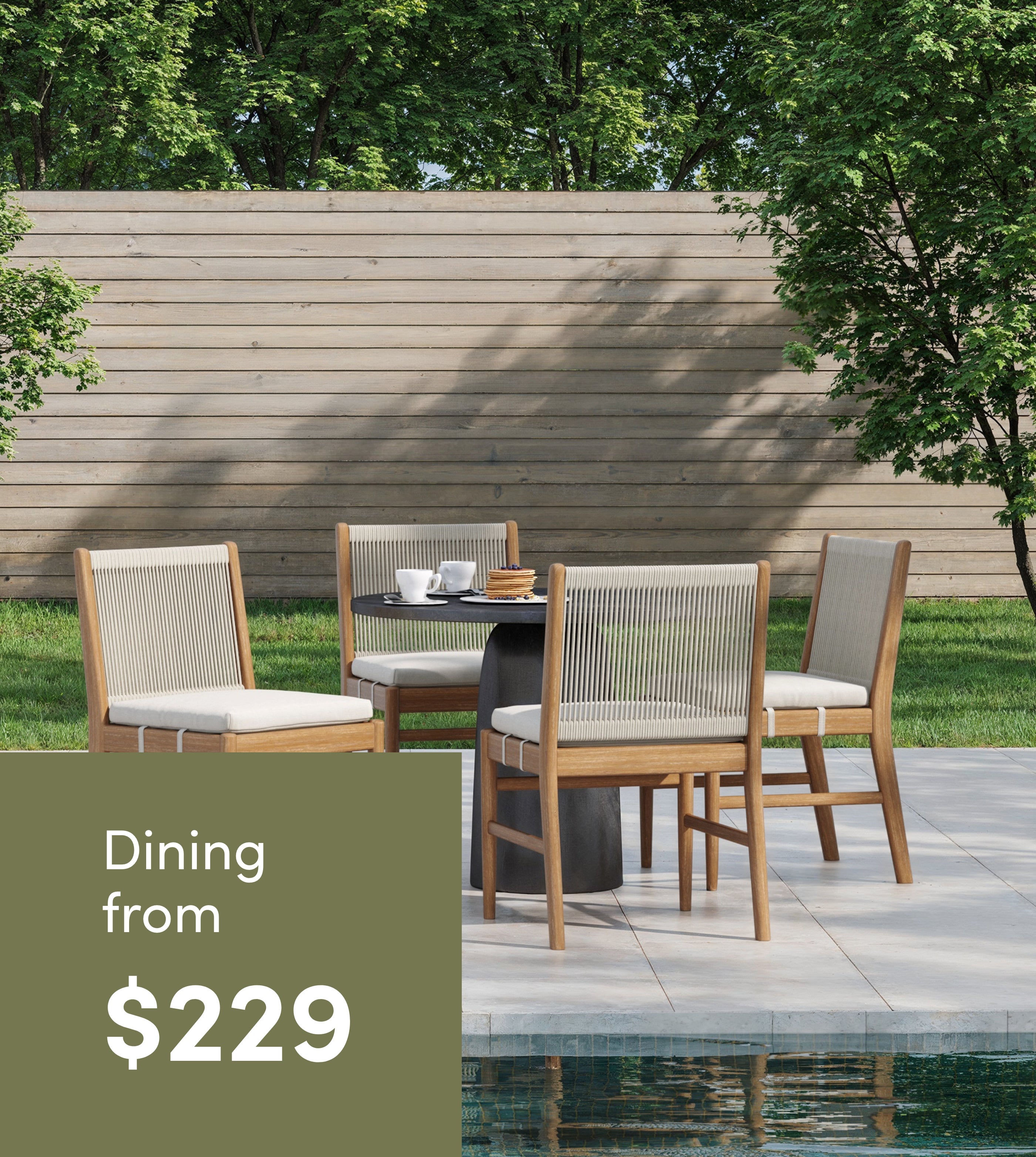 Outdoor dining set with four wooden chairs and a round table arranged on a stone patio by a pool, surrounded by green lawn, trees, and a wooden fence; text reads Dining from $229.