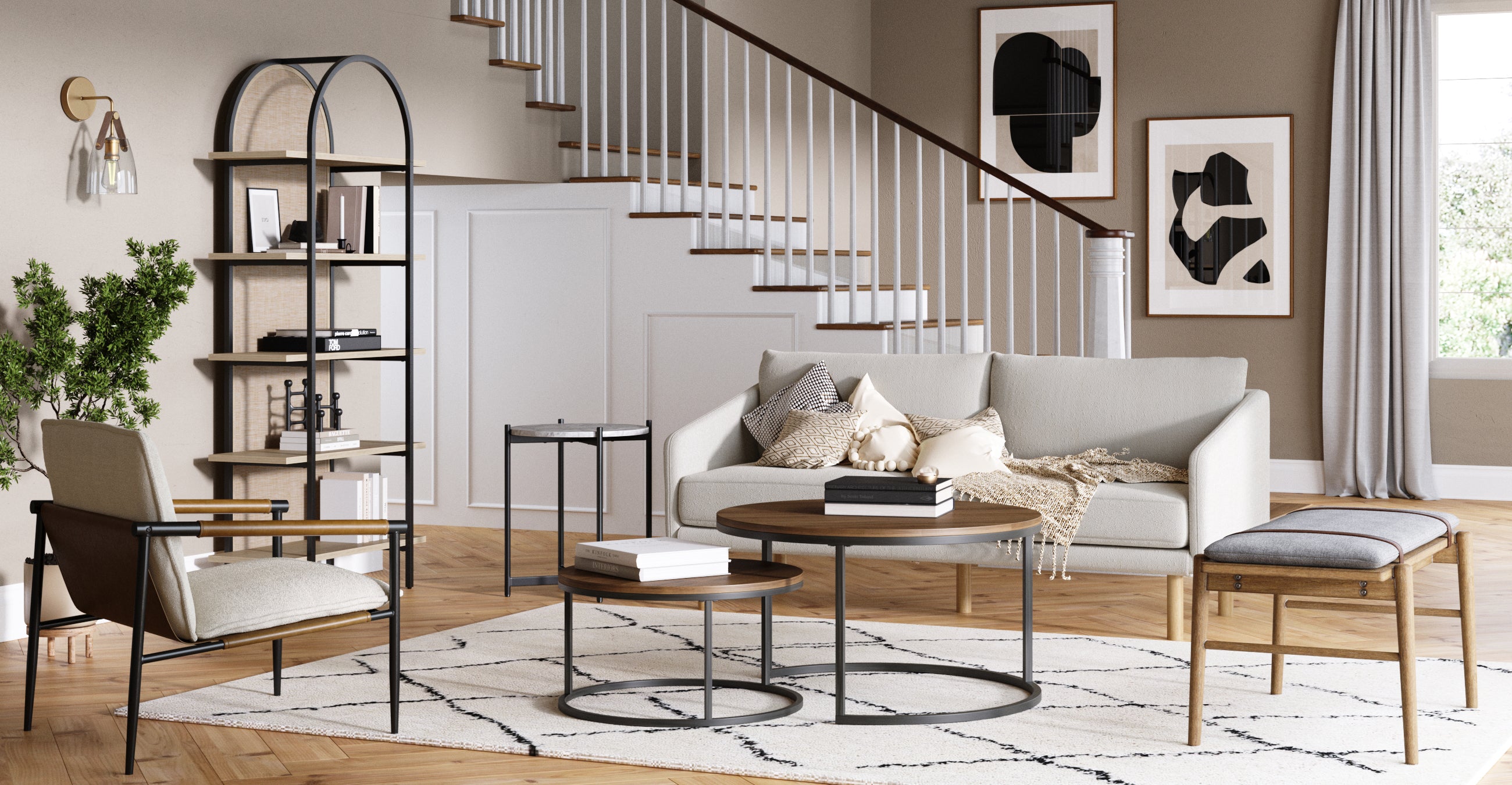 A modern living room with neutral tones features a light gray sofa, armchair, wooden bench, circular coffee tables, a tall bookshelf, abstract wall art, and a staircase in the background. A rug and plants complete the decor.
