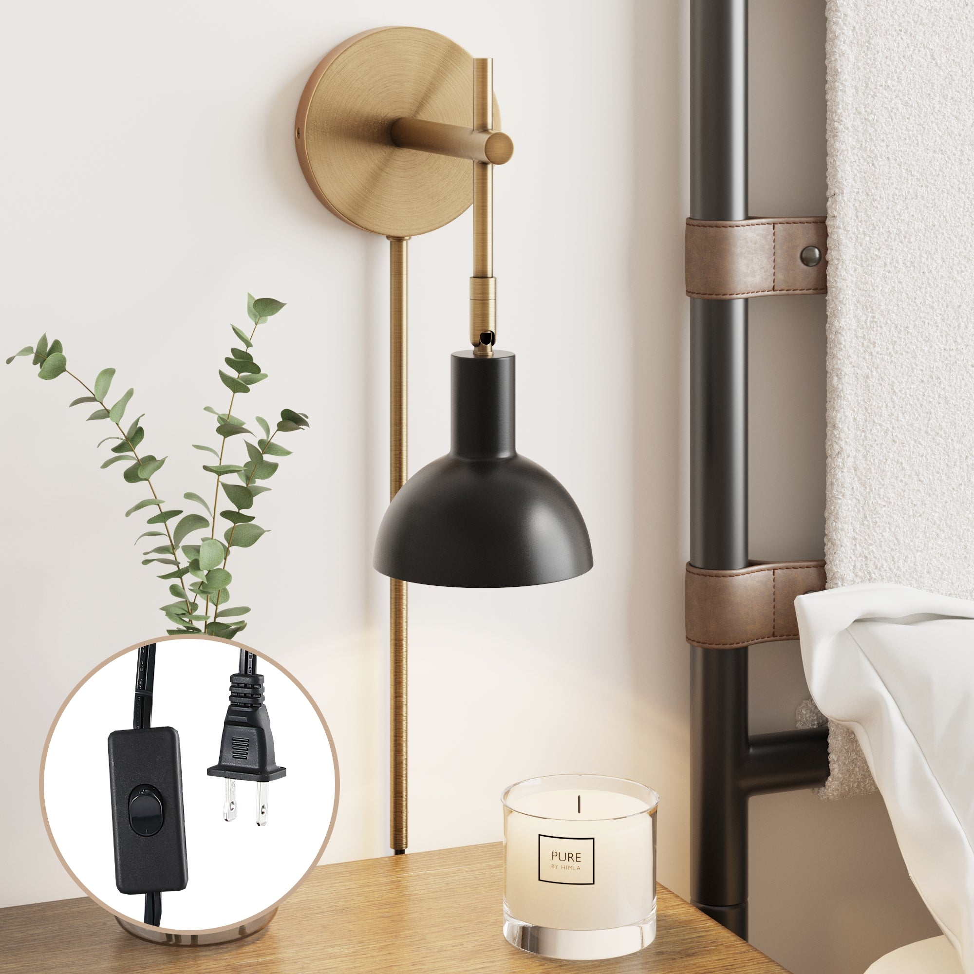 A Plug-In Adjustable Metal Wall Light Brass by Nathan James is mounted beside a bed. On the bedside table below are a eucalyptus branch in a vase, a candle, and an inset detail of the lamp’s switch and plug.