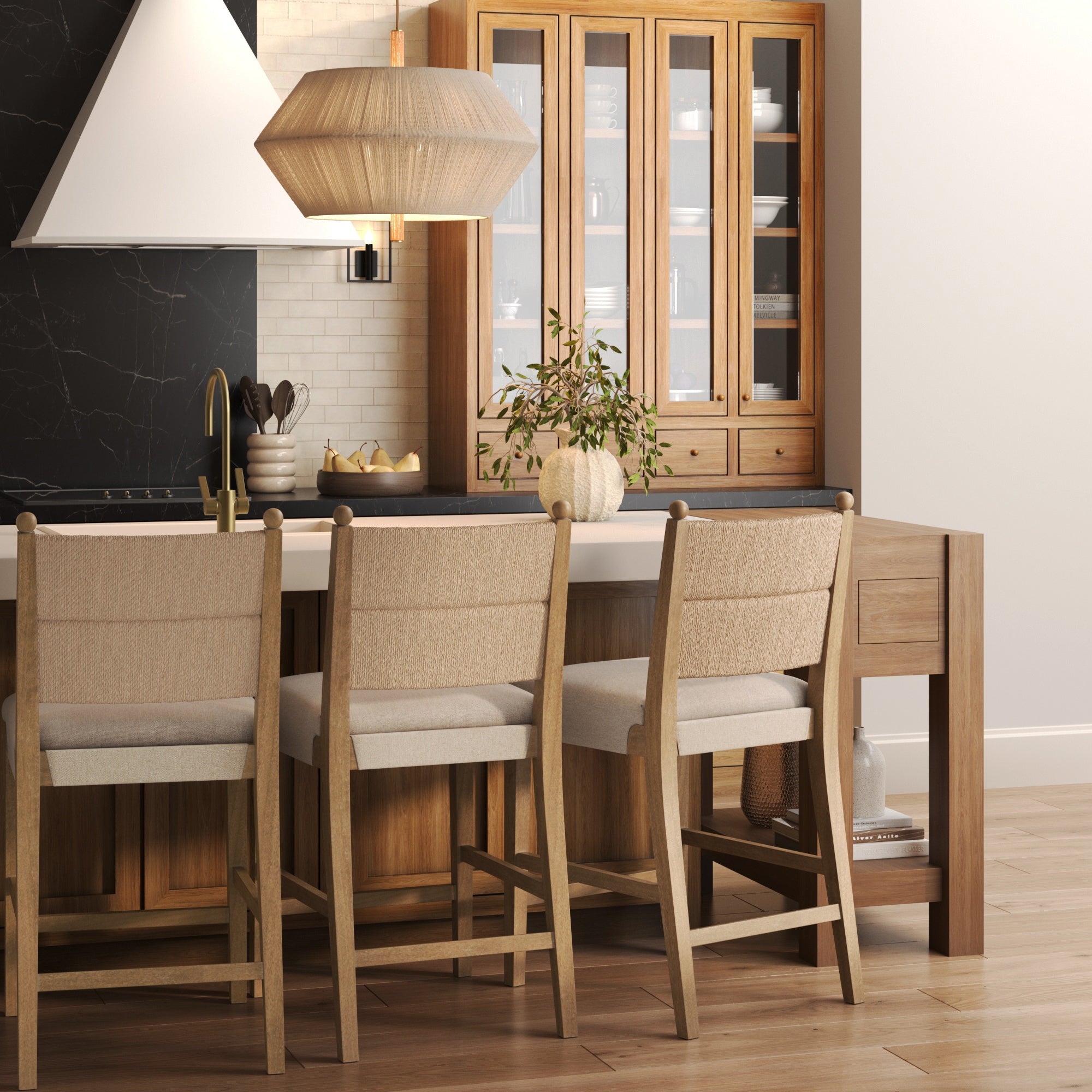 A modern kitchen with wood cabinets, a white countertop, and a woven pendant light features Nathan James Seagrass & Wood Counter Height Bar Stools in light brown (set of 3) for comfortable seating at the island.