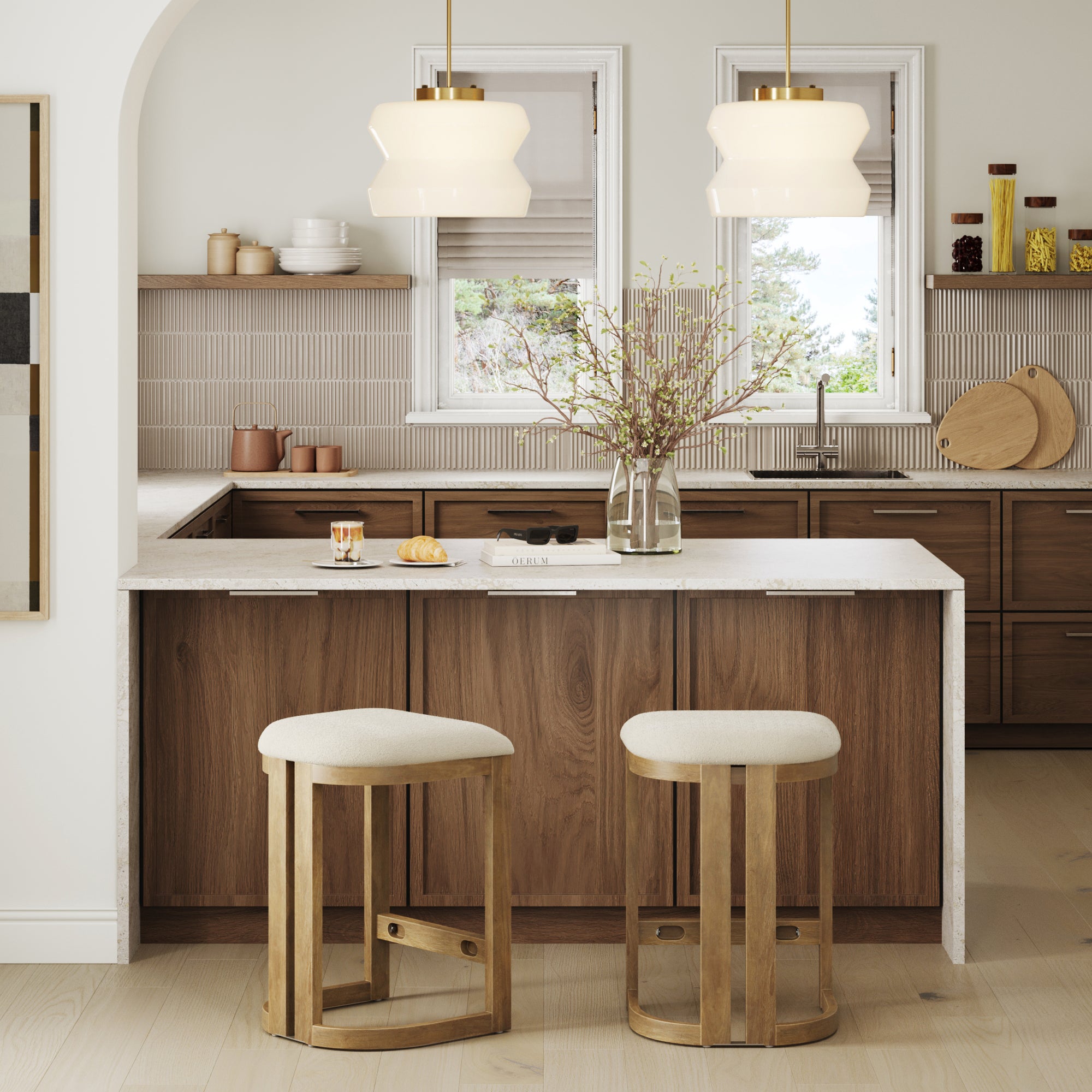 Modern kitchen with solid wood cabinets, a white island countertop, pendant lights, minimalist decor, and two Nathan James Barrel Wooden Backless Bar Stools in light brown with upholstered seats.