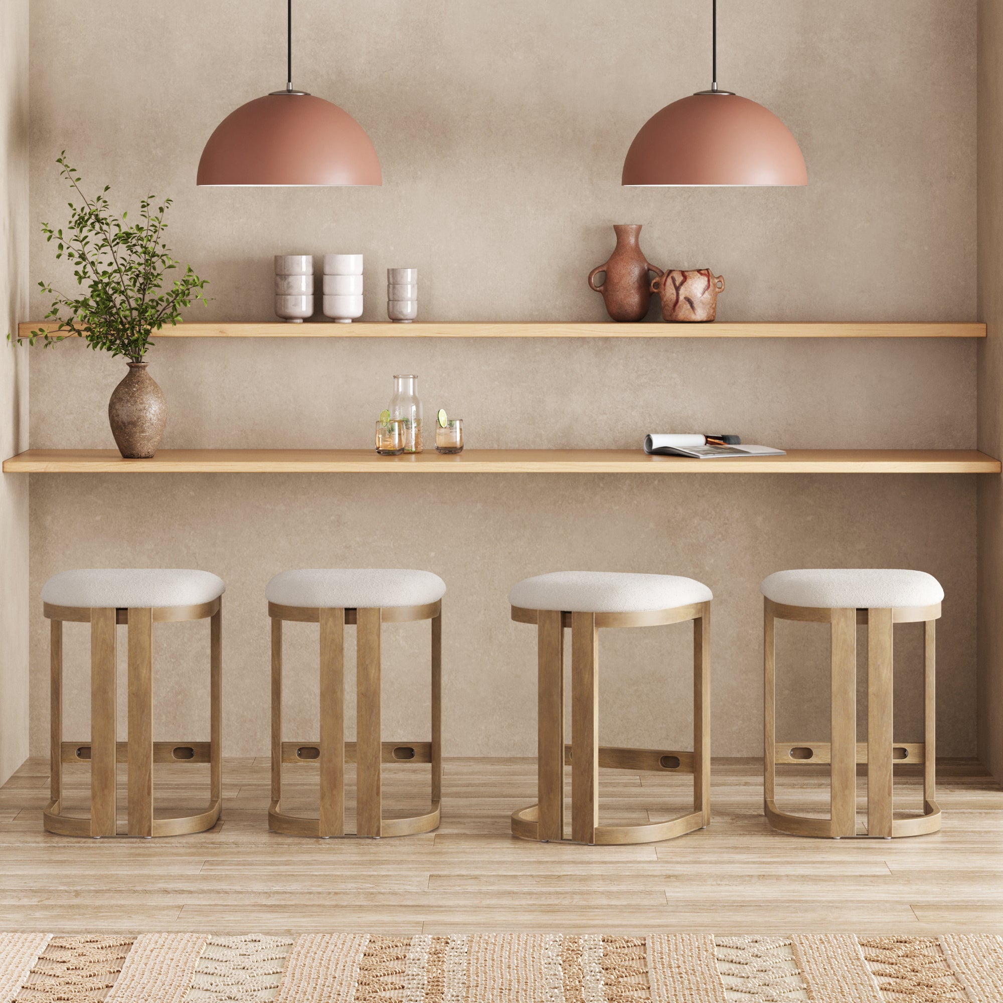A minimal kitchen features a set of four Nathan James Barrel Wooden Backless Bar Stools in light brown at the counter, two pendant lights above, floating shelves with vases, cups, and plants, and a light neutral color palette.