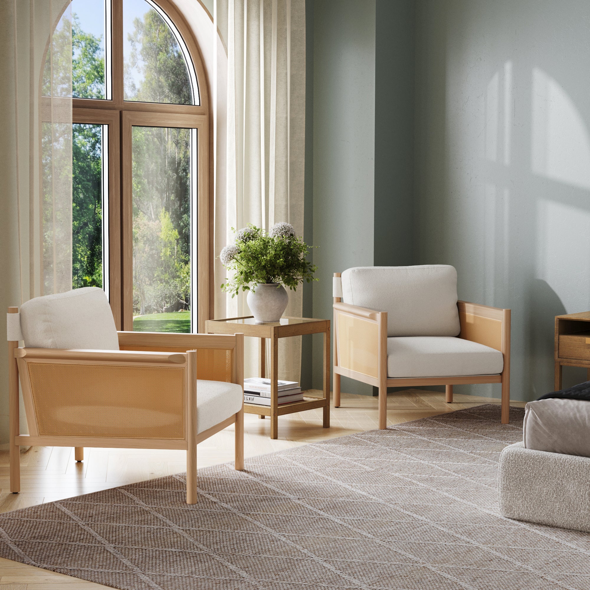 A bright, modern living room featuring Nathan James Solid Wood Boucle Accent Chairs with raw oak and rattan arms (set of 2), a small side table with a potted plant, large arched window with beige curtains, and a textured area rug on wooden floors.