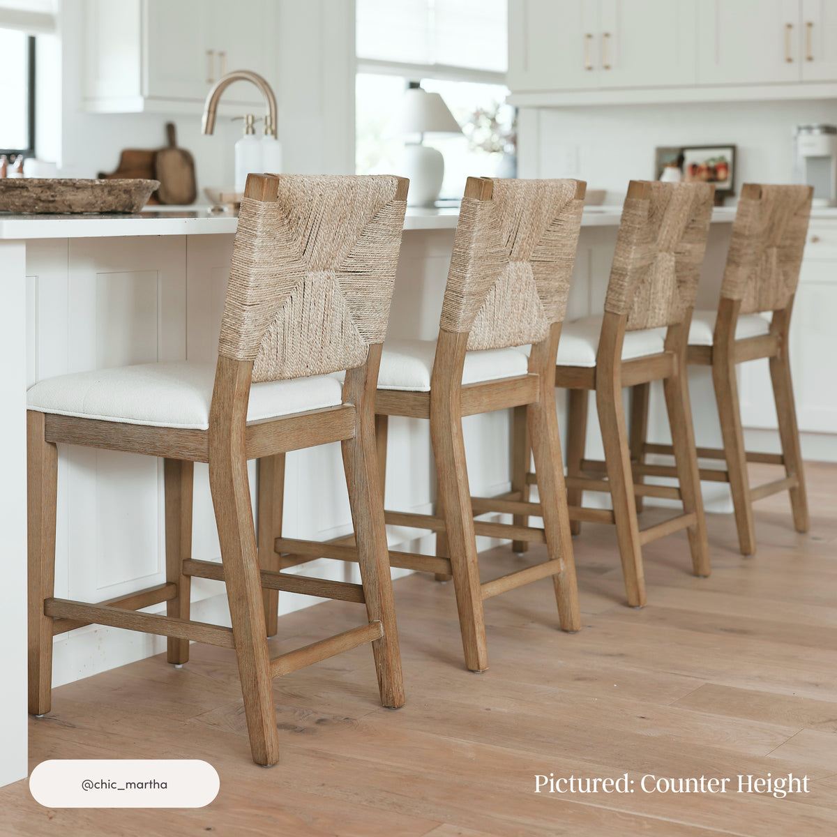 Four Nathan James Boucle & Seagrass Bar Stool Light Brown (Set of 2) counter-height stools with wooden frames, white boucle fabric seats, and woven seagrass backrests lined up at a kitchen island.