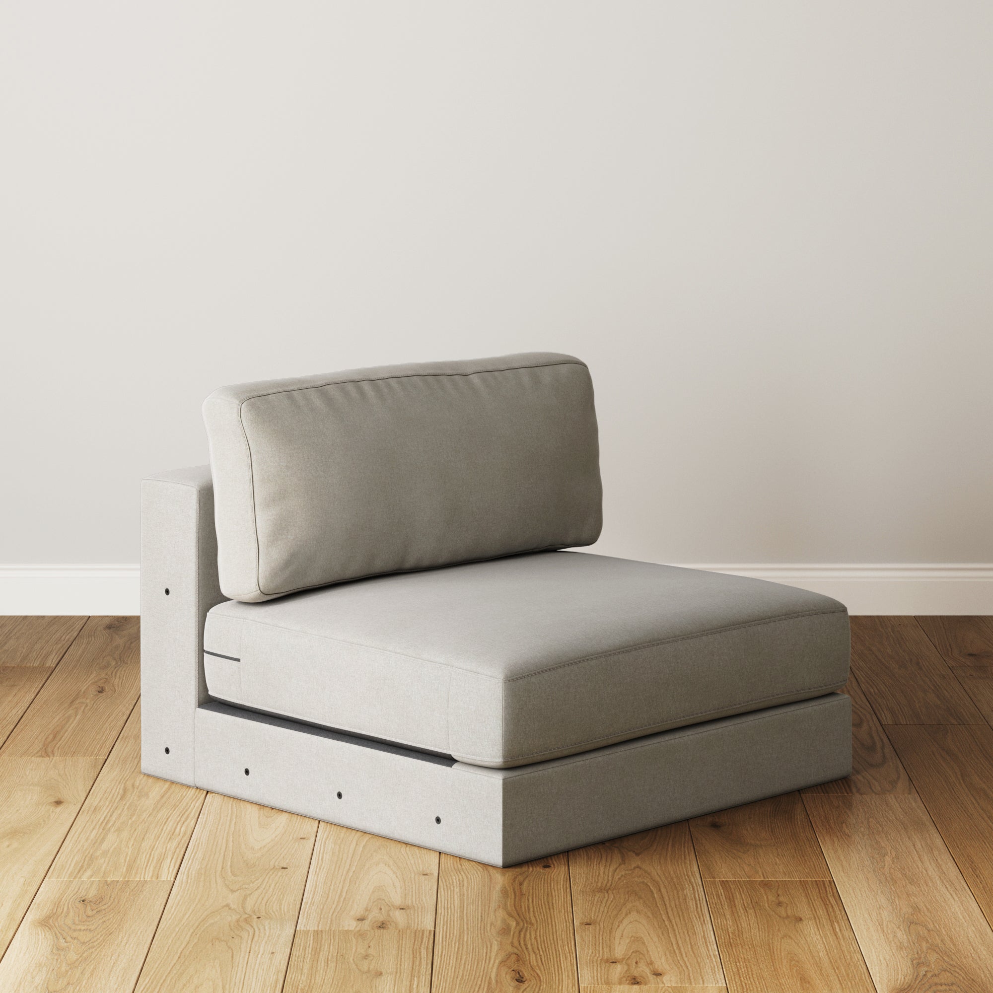 The Nathan James Upholstered Sofa Standard Seat (Modular Sofa Part) features a textured gray cushion, plush back cushions, and a minimalist boxy design, shown armless on a wooden floor against a plain off-white wall.