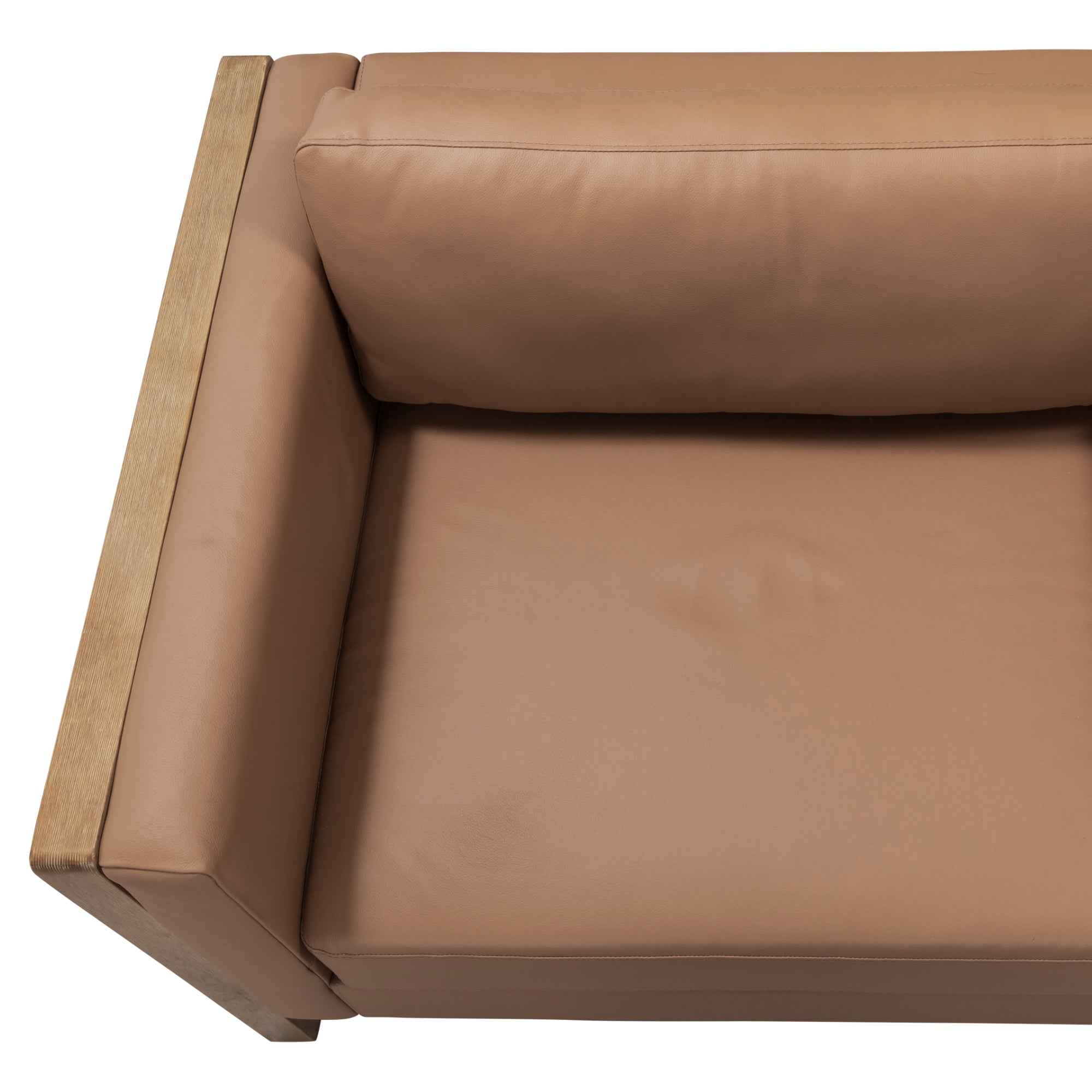 A top-down view of a modern armchair with a tan leather cushion and wooden armrest and frame on the left side. The cushion appears smooth and well-padded.