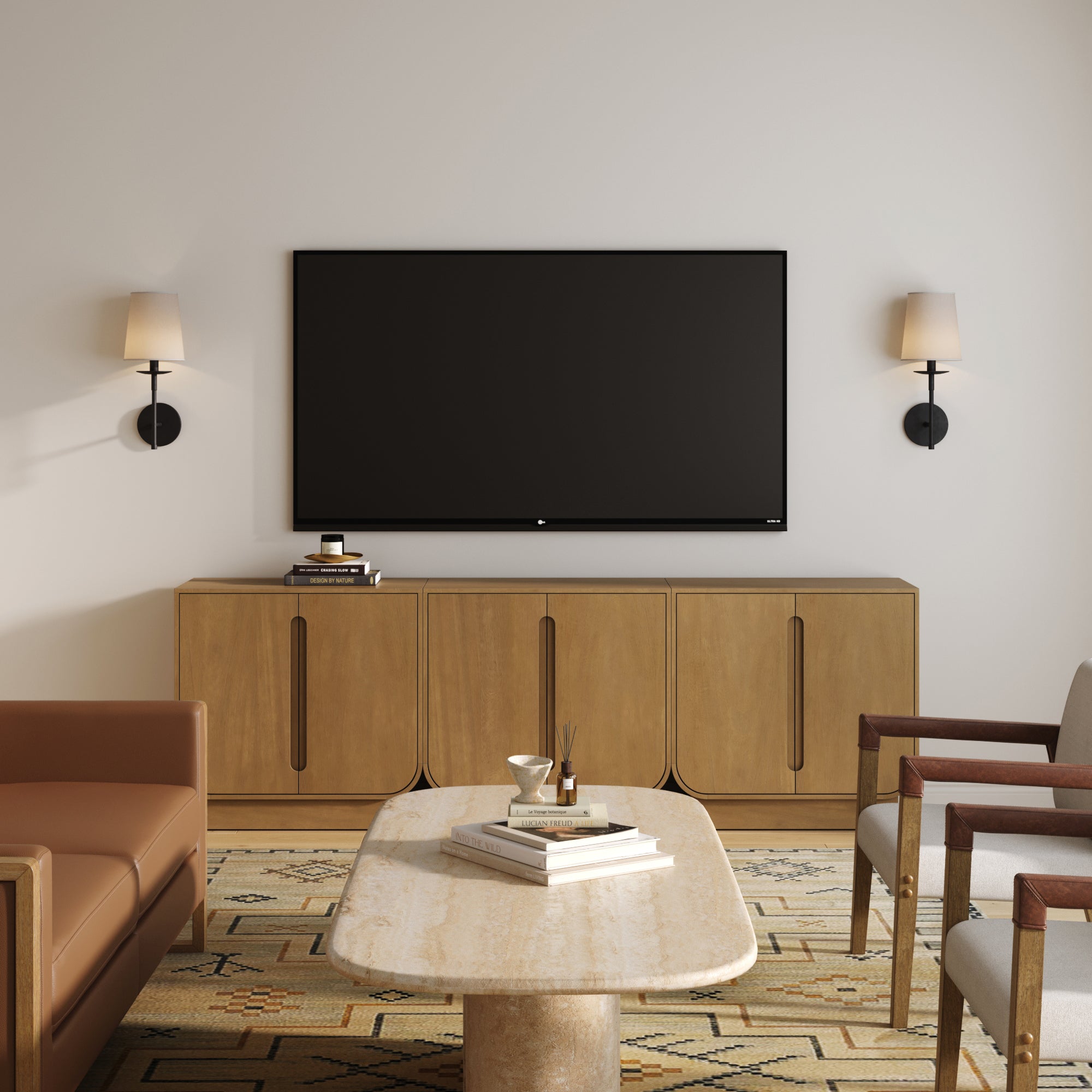 A modern living room features a wall-mounted TV above the Nathan James Veneer Arched Accent Cabinet or TV Stand Light Brown (Set of 3), flanked by wall sconces, with a marble coffee table and mixed-material armchairs on a patterned rug.