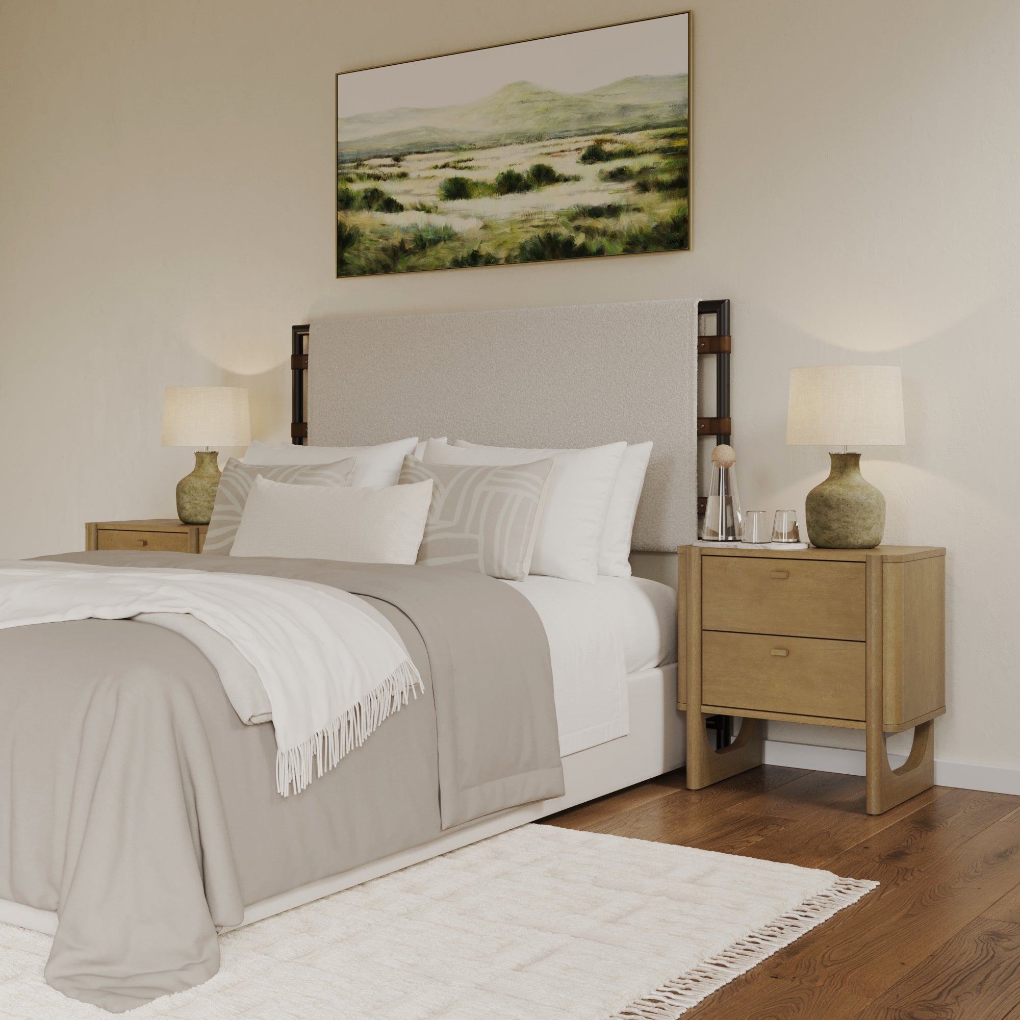 A cozy bedroom with a beige and white bed, two wooden nightstands with lamps, a soft rug, and a landscape painting above the headboard. The room has warm lighting and neutral-toned decor.