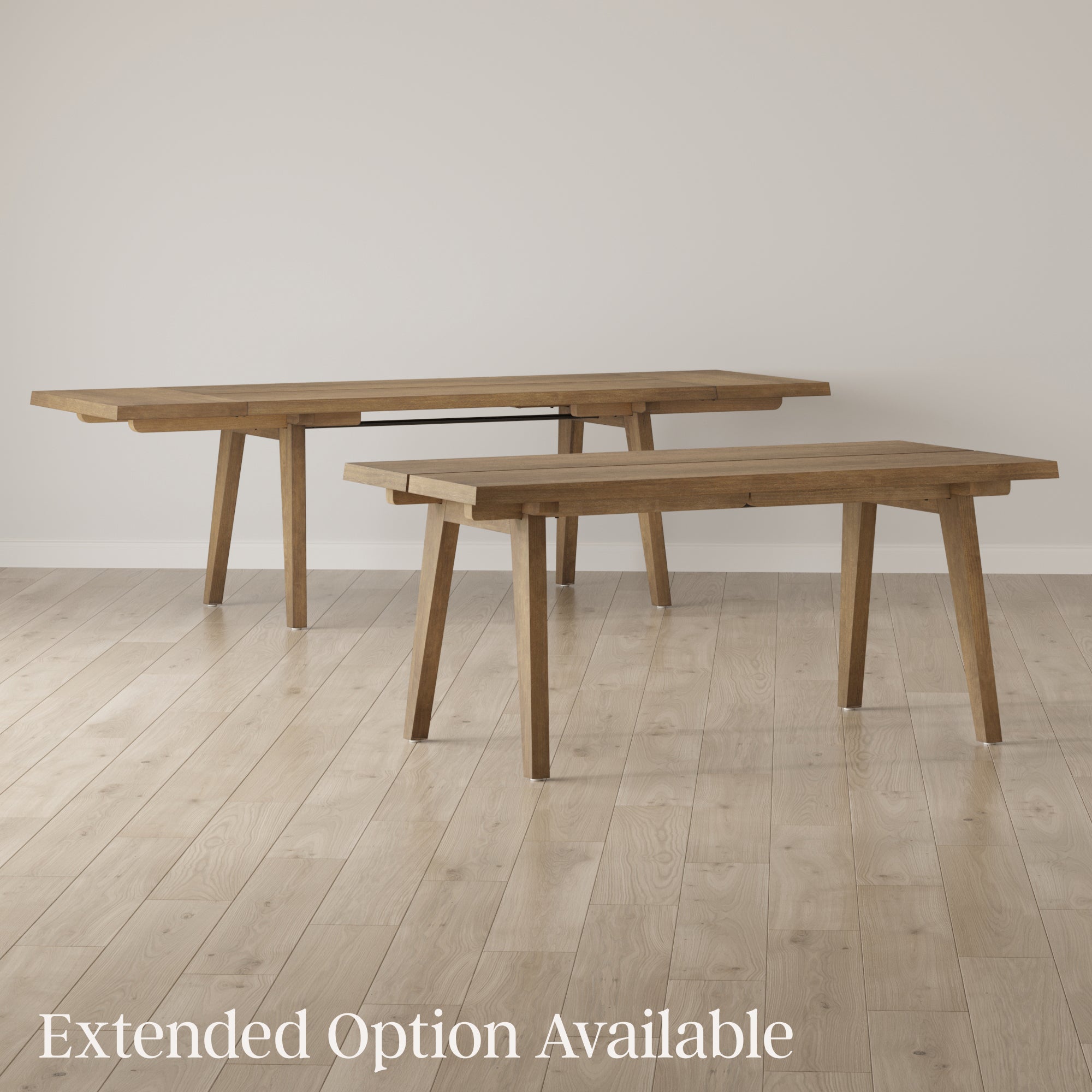 Two wooden tables stand on a light wood floor against a plain, light-colored wall. One table is extended to show its larger option. Text in the lower left corner reads, Extended Option Available.