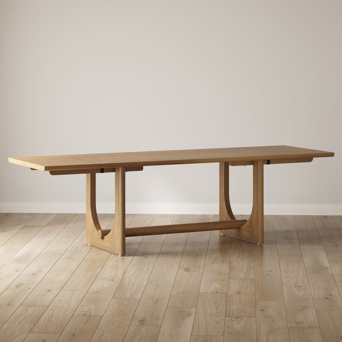 A modern, rectangular wooden dining table with clean lines and a geometric base stands on a light wood floor against a plain, light-colored wall.