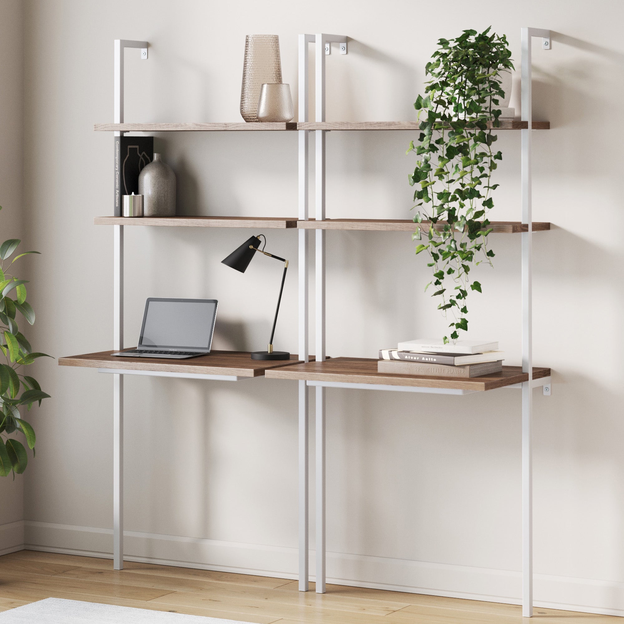 The Nathan James Wood Wall Mount Ladder Desk Oak (Set of 2) features rustic oak shelves, perfect for a small space desk setup with a laptop, lamp, books, and decor—stylish and space-saving against a light wall with greenery.