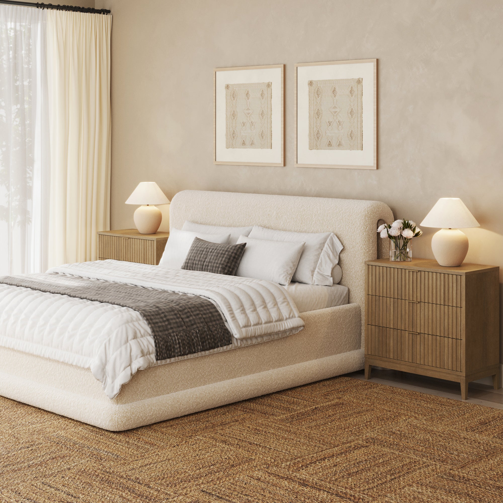 Cozy bedroom with a low cream upholstered bed, neutral bedding, two wooden nightstands with lamps, framed art on the wall, and a large woven rug over a light floor by a window with cream curtains.